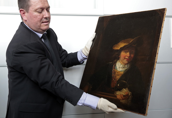 Colonel Stephane Goffeni holds the painting "L'enfant a la bulle de savon, 1630" attributed to painter Rembrandt during a presentation to journalists at the court in Nice