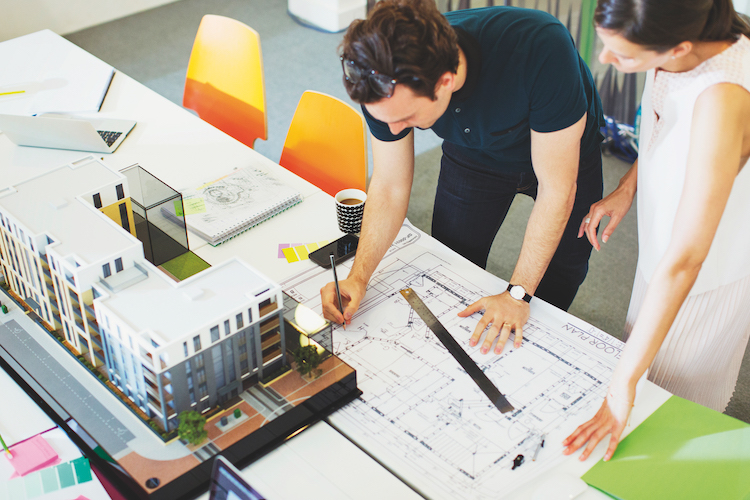 Architects drafting blueprint in office